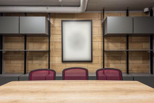 Modern boardroom with a wooden table, mesh chairs and fitted shelving
