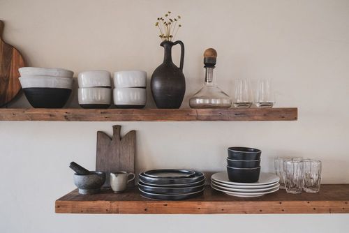 Ceramic bowls, plates and glassware on a wooden shelf