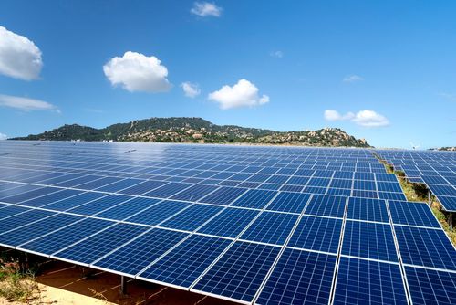 Rows of solar panels in a field under a blue sky